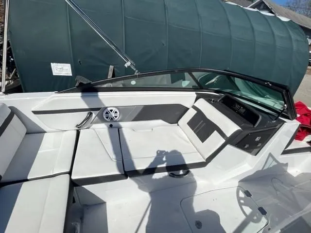 Slide: The Image of 2022 Monterey M22 boat interior with seating and dashboard, under a green cover. - 11