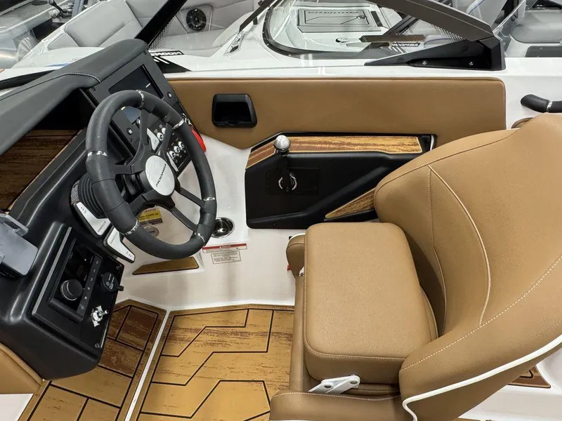 Slide: The Image of 2025 Moomba Max boat interior with tan seating, steering wheel, and wood accents. - 14