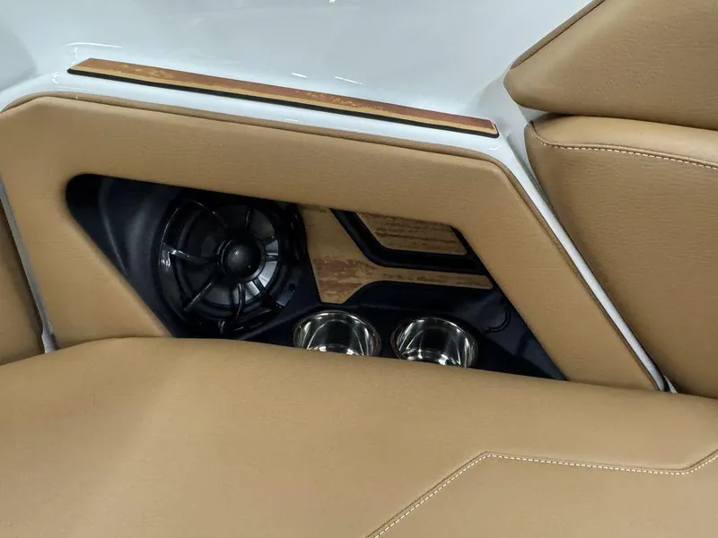 Slide: The Image of 2025 Moomba Max interior detail with tan upholstery, speaker, and cup holders. - 16