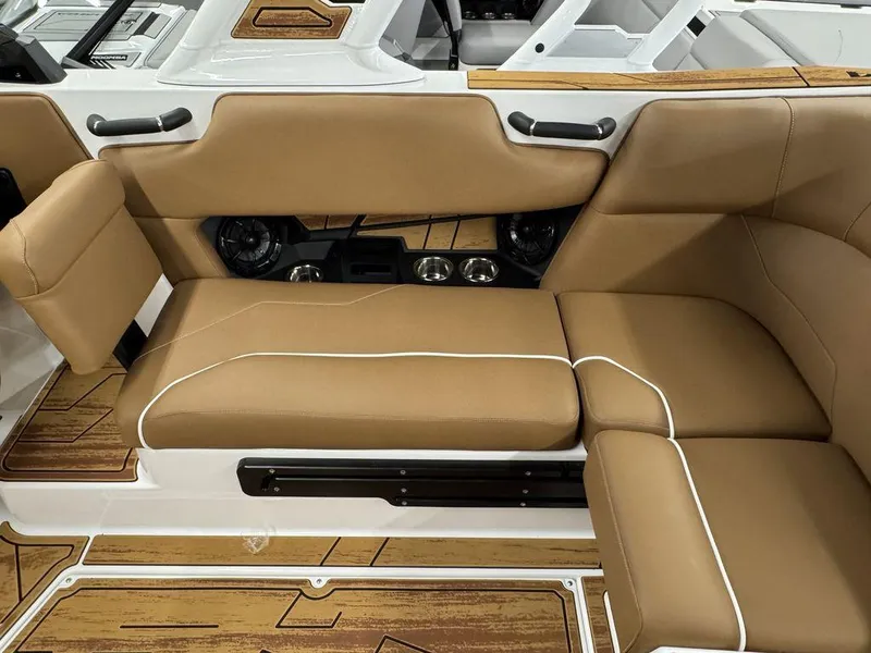 Slide: The Image of 2025 Moomba Max interior with tan seating, cup holders, and wood-patterned flooring. - 9