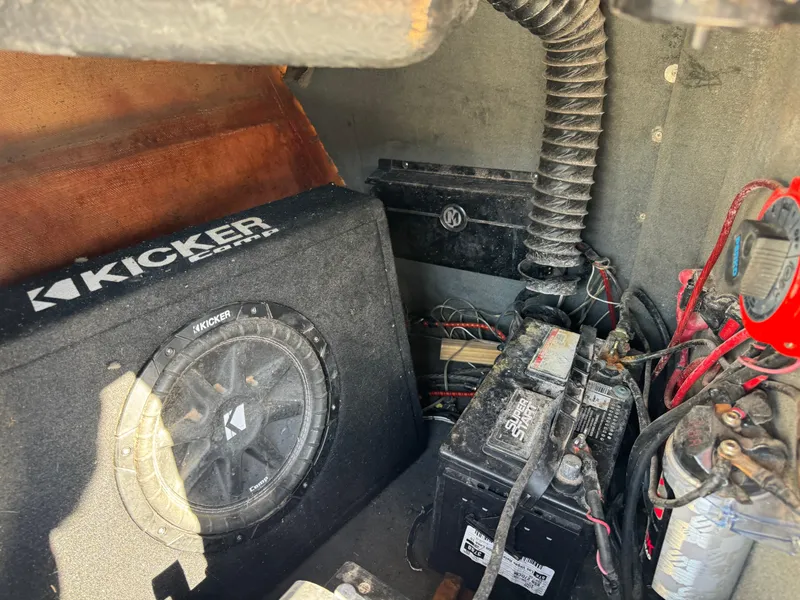 Slide: The Image of 2003 Malibu Wakesetter 23 XTi boat interior with Kicker subwoofer and battery setup. - 12