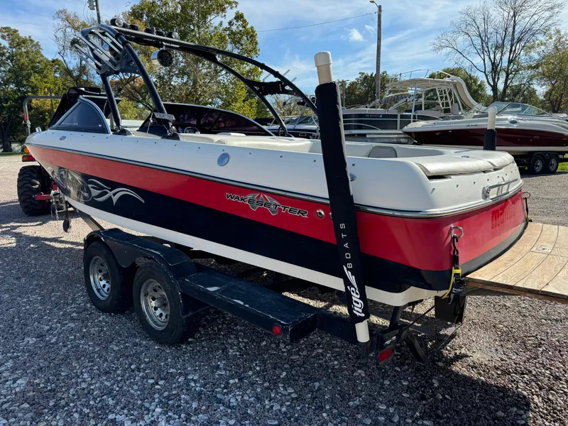 Slide: The Image of 2003 Malibu Wakesetter 23 XTi boat on trailer, red and white design, parked outdoors. - 3