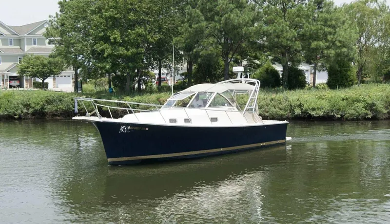 Slide: The Image of 2004 Mainship Pilot 30-II cruising on a calm river near lush greenery. - 1