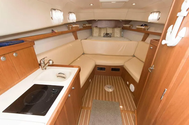 Slide: The Image of 2004 Mainship Pilot 30-II cabin interior with kitchenette, seating, and bed. - 7