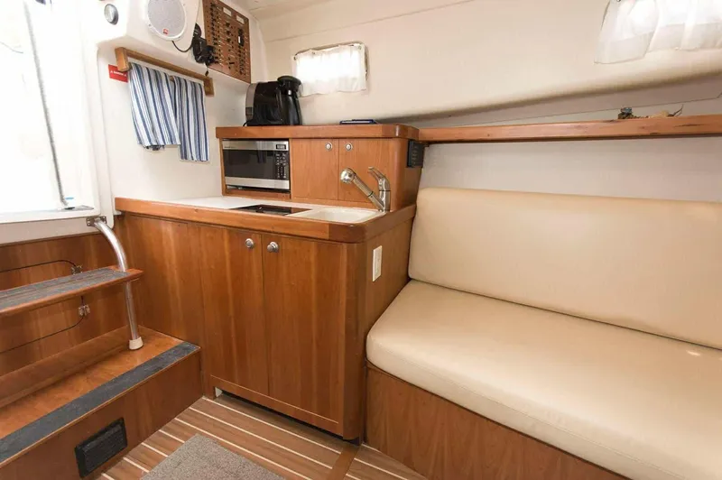 Slide: The Image of 2004 Mainship Pilot 30-II interior with kitchenette, microwave, and seating area. - 8