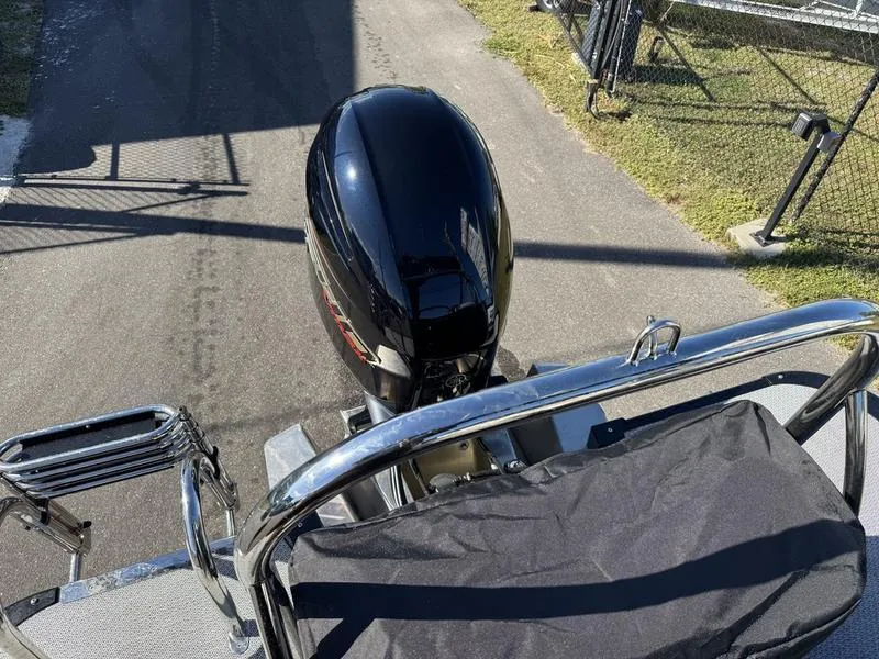 Slide: The Image of 2025 Avalon LSZ Quad Lounger boat with powerful outboard motor, parked on pavement. - 11