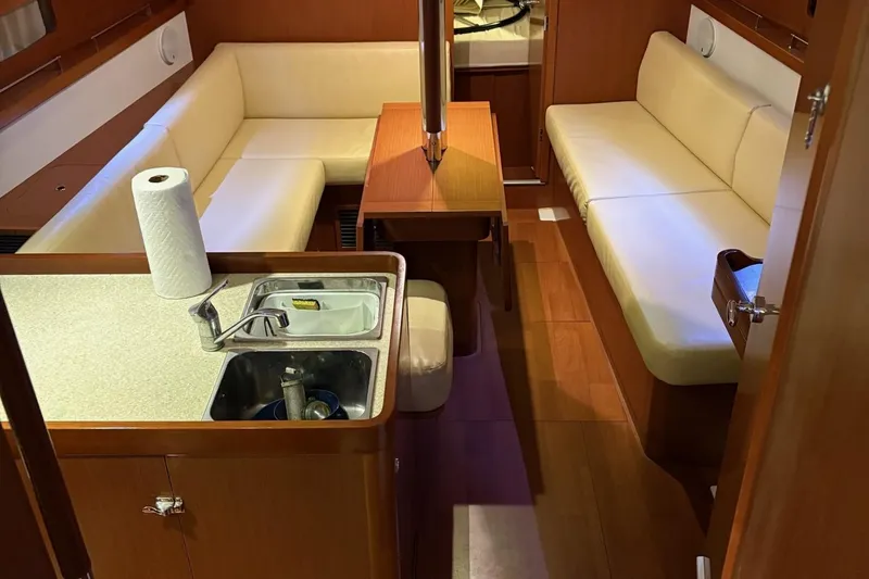 Slide: The Image of Interior of 2013 Beneteau Oceanis 34 sailboat with cozy seating and compact kitchen area. - 14