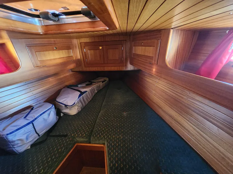 Slide: The Image of Wood-paneled cabin interior of a 2000 Regina 43 boat, featuring storage compartments and bags. - 23