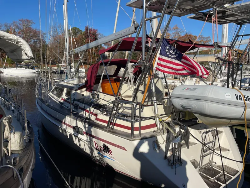 Slide: The Image of Sailboat "Regina 43" docked, featuring an American flag and inflatable dinghy, autumn trees in background. - 4