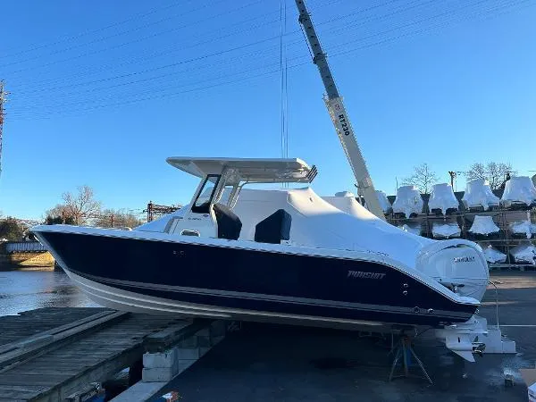 Slide: The Image of 2025 Pursuit S 268 Sport boat on dock, blue hull, white top, crane in background. - 2