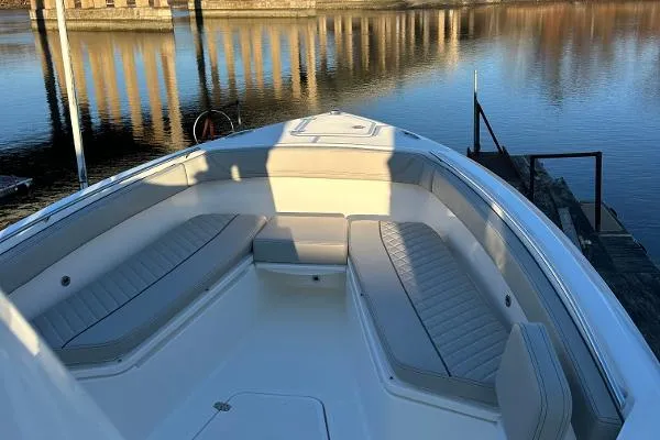 Slide: The Image of 2025 Pursuit S 268 Sport boat interior with cushioned seating, docked by calm water. - 5