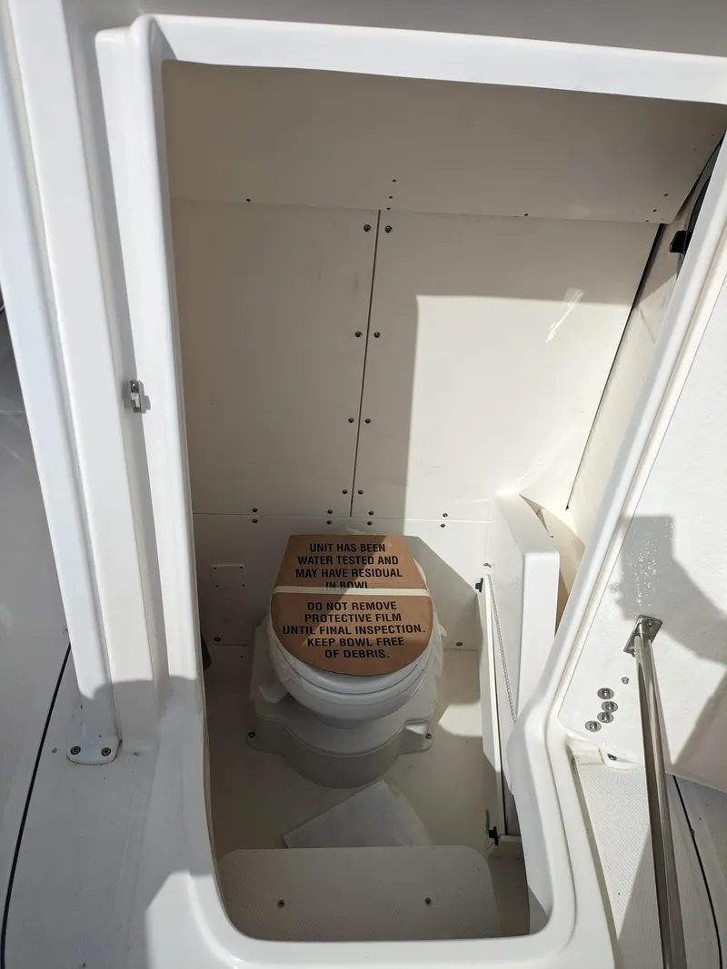 Slide: The Image of 2025 Robalo R230 Center Console boat interior with compact marine toilet. - 22