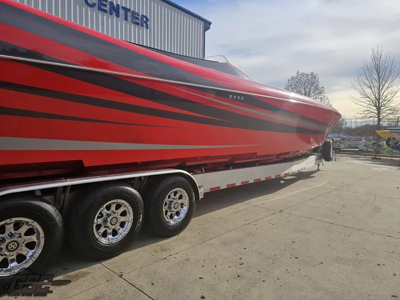 Slide: The Image of 2010 Outerlimits 52 SL speedboat with red and black stripes on a trailer. - 14