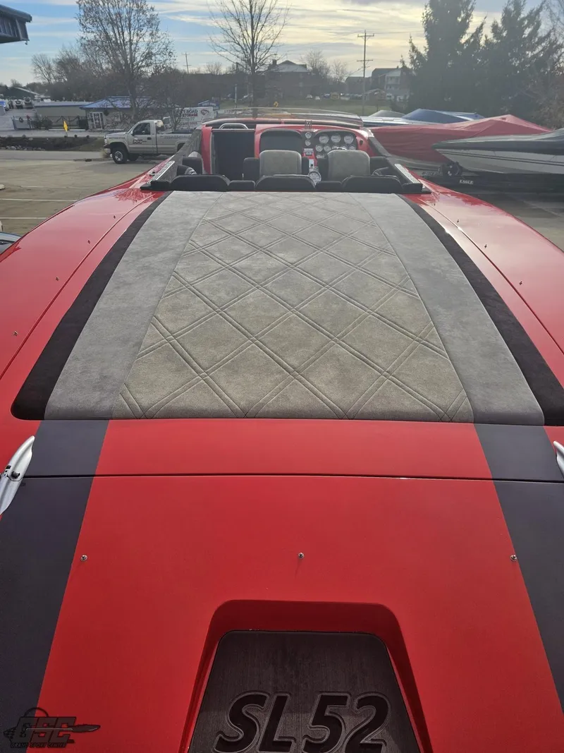 Slide: The Image of 2010 Outerlimits 52 SL speedboat with red and gray detailing, docked outdoors. - 49