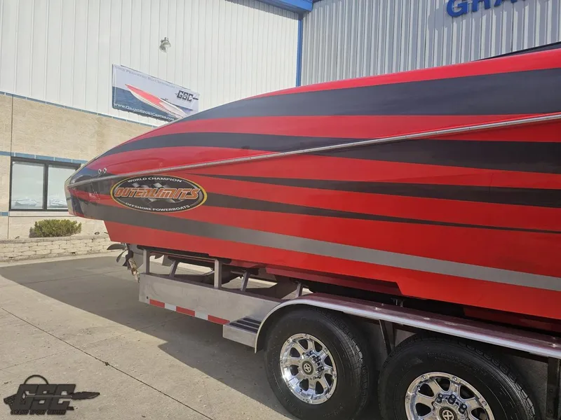 Slide: The Image of 2010 Outerlimits 52 SL powerboat on trailer, red and black design, parked outside building. - 6