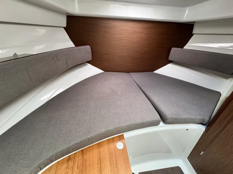 Slide: The Image of 2025 Beneteau Antares 8 cabin interior with cushioned seating and wood accents. - 16