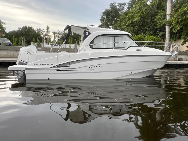 Slide: The Image of 2025 Beneteau Antares 8 boat on calm water, side view, surrounded by greenery. - 2