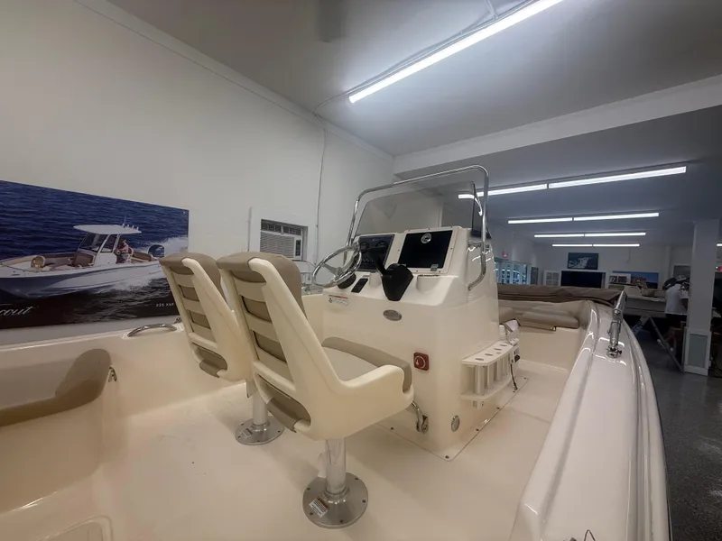Slide: The Image of 2024 Scout 175 Sportfish boat interior with dual seats and control panel in showroom. - 5