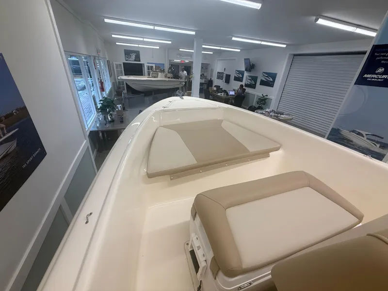 Slide: The Image of 2024 Scout 175 Sportfish boat interior in showroom, featuring beige seating and modern design. - 7