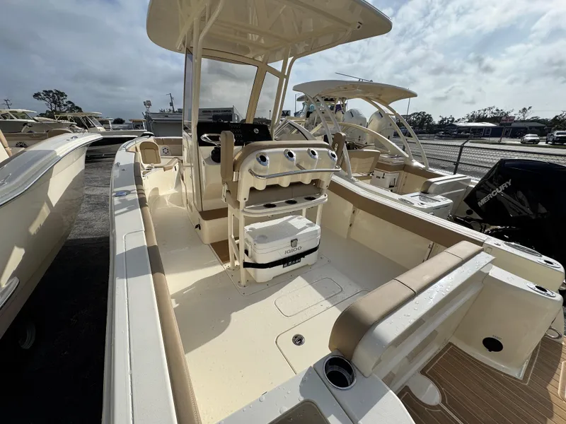 Slide: The Image of 2025 Scout 240 XSF boat interior with seating and console, parked outdoors. - 4