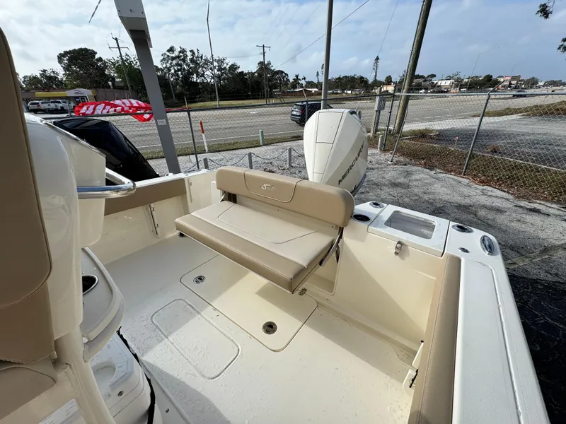 Slide: The Image of 2025 Scout 240 XSF boat interior with seating and motor, parked outdoors. - 5