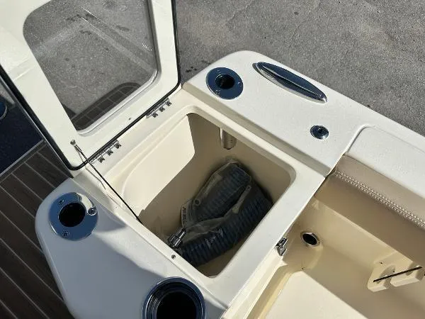 Slide: The Image of 2025 Scout 240 XSF boat storage compartment with open hatch and hose. - 6