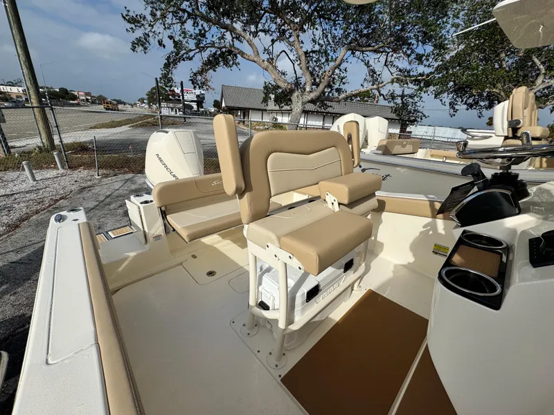 Slide: The Image of 2025 Scout 240 XSF boat interior with beige seating and console, parked outdoors. - 8