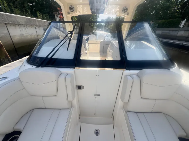 Slide: The Image of 2025 Scout 277 Dorado boat interior with white seating and windshield, docked by a canal. - 12