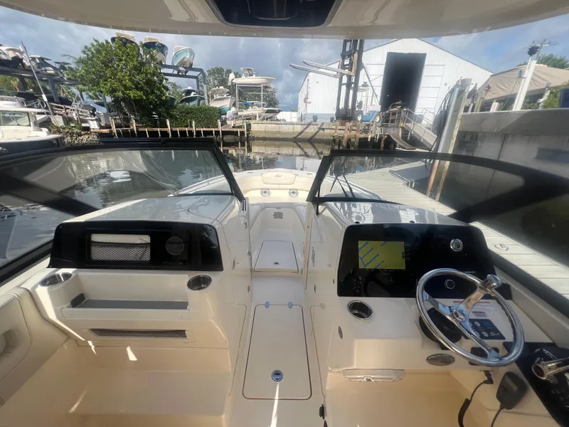Slide: The Image of 2025 Scout 277 Dorado boat interior with steering wheel and navigation system at a marina. - 13