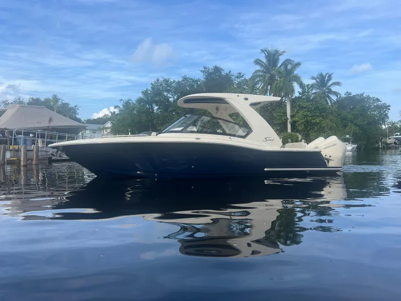 Slide: The Image of 2025 Scout 277 Dorado boat on calm water with trees in the background. - 2