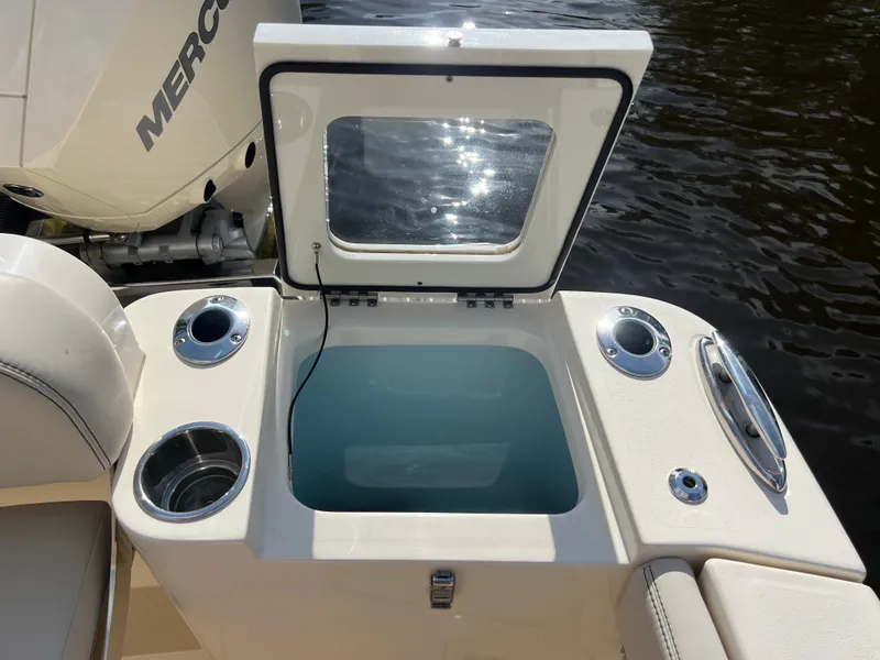 Slide: The Image of 2025 Scout 277 Dorado boat with open livewell and cup holders, docked by water. - 26