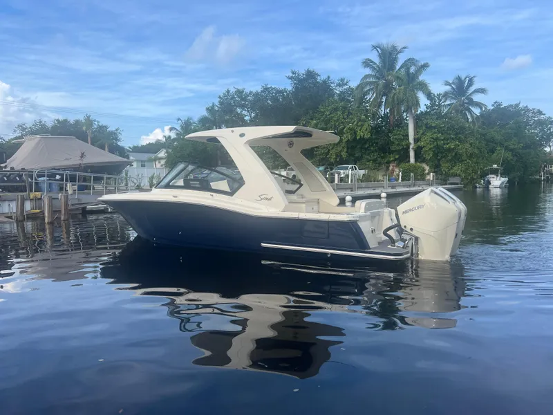 Slide: The Image of 2025 Scout 277 Dorado boat on calm water with lush greenery background. - 3