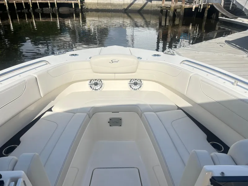 Slide: The Image of 2025 Scout 277 Dorado boat interior with white seating and speakers, docked by calm water. - 8