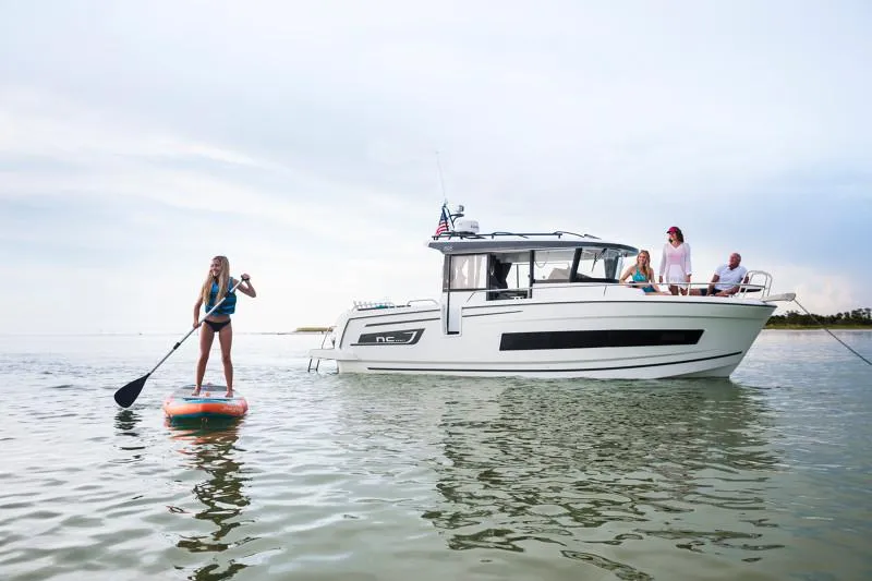 Slide: The Image of 2024 Jeanneau NC Sport 895 boat with people enjoying paddleboarding nearby. - 10