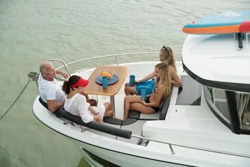Slide: The Image of People relaxing on a 2024 Jeanneau NC Sport 895 boat, enjoying drinks and conversation. - 18