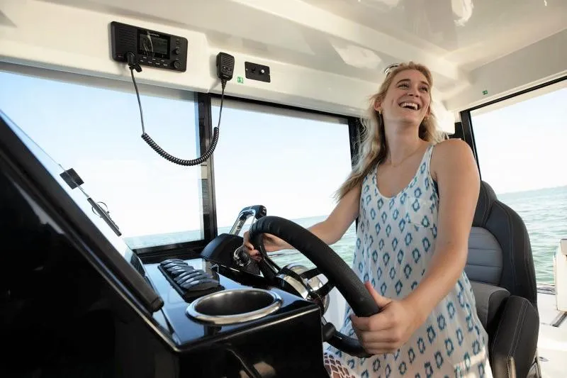 Slide: The Image of Woman steering 2024 Jeanneau NC Sport 895 boat, smiling and enjoying the ride. - 20