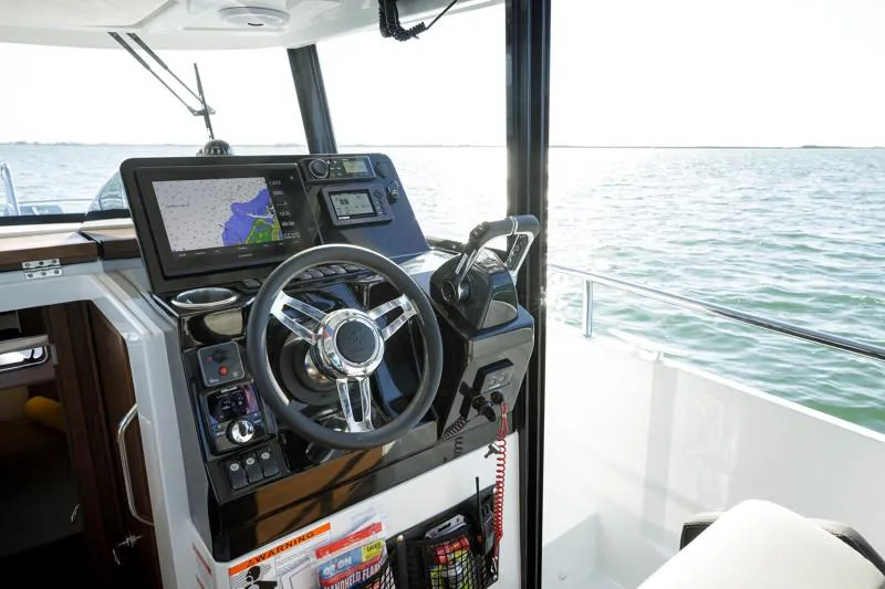 Slide: The Image of 2024 Jeanneau NC Sport 895 helm with navigation system, steering wheel, and ocean view. - 14
