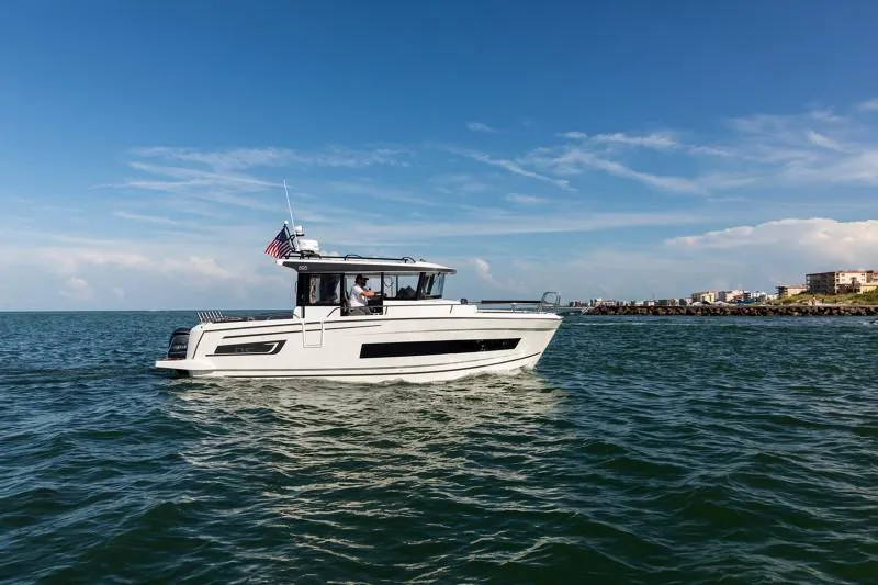 Slide: The Image of 2024 Jeanneau NC Sport 895 boat cruising on open water under a clear blue sky. - 2