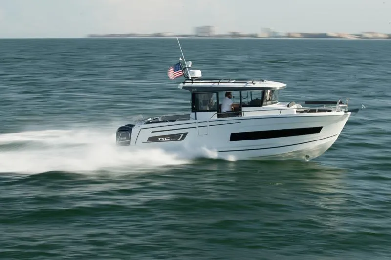 Slide: The Image of 2024 Jeanneau NC Sport 895 cruising on open water, American flag flying. - 6