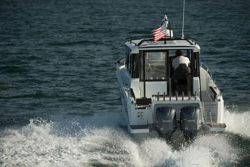 Slide: The Image of 2024 Jeanneau NC Sport 895 cruising on open water, rear view with American flag. - 8