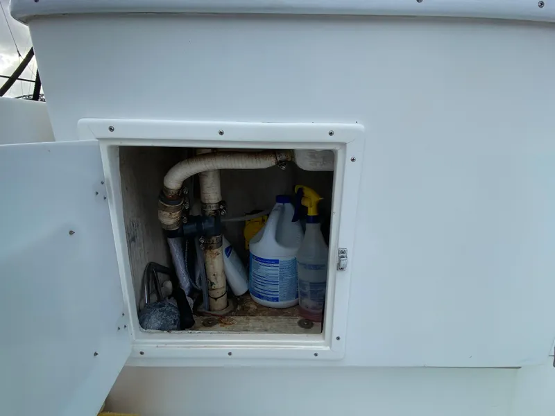 Slide: The Image of Storage compartment on 1998 Contender 35 Express boat with cleaning supplies and plumbing. - 13
