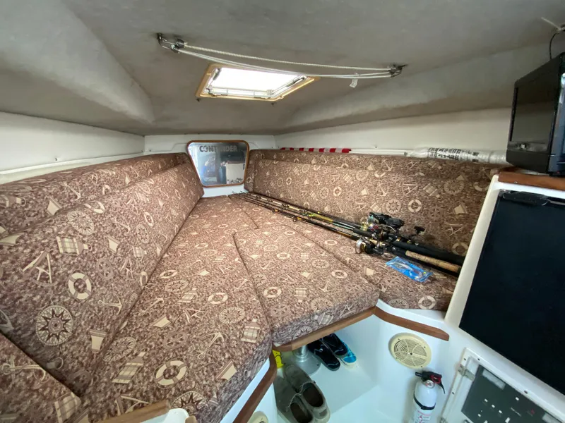 Slide: The Image of 1998 Contender 35 Express cabin with patterned cushions and fishing rods. - 38