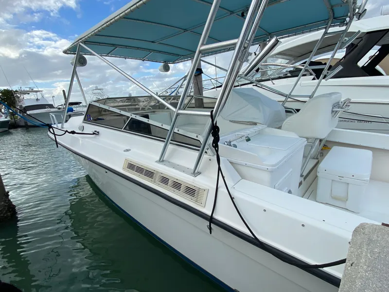 Slide: The Image of 1998 Contender 35 Express boat docked in marina, featuring blue canopy and sleek design. - 4