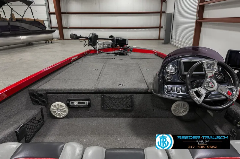 Slide: The Image of 2018 Triton 18 TX boat interior with steering wheel and control panel in a warehouse. - 15
