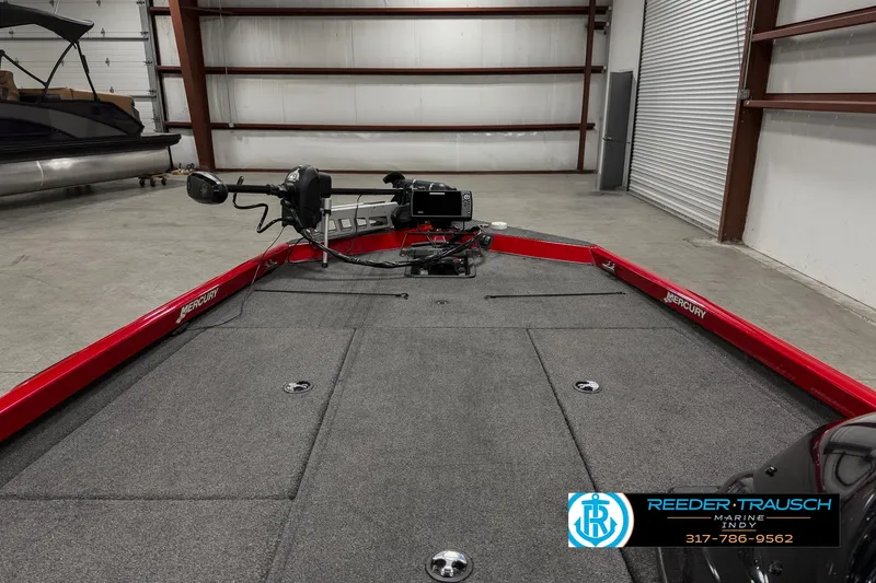 Slide: The Image of 2018 Triton 18 TX boat interior with red trim and fishing equipment in a garage. - 16