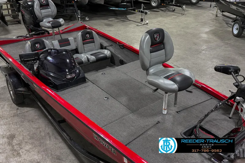 Slide: The Image of 2018 Triton 18 TX fishing boat with red trim and gray seating in showroom. - 17