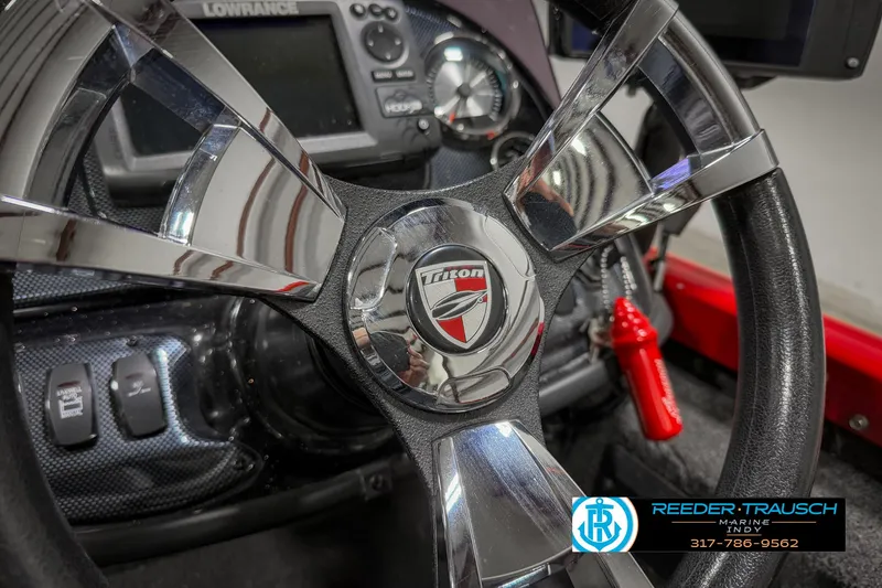 Slide: The Image of Steering wheel of a 2018 Triton 18 TX boat with dashboard controls. - 28