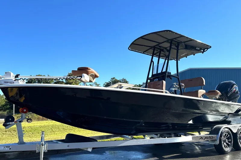 Slide: The Image of 2026 Avid 23 Fusion boat on trailer, featuring sleek design and canopy under clear blue sky. - 1