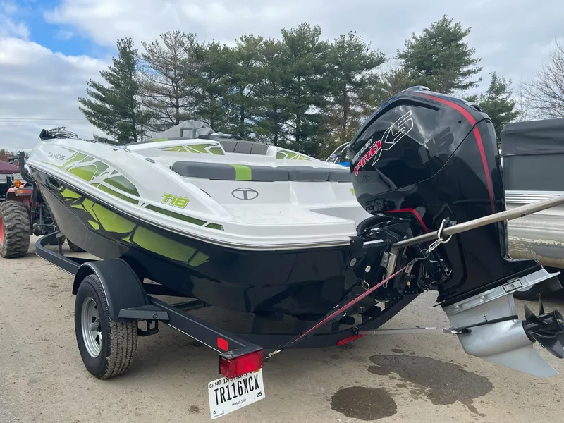 Slide: The Image of 2021 Tahoe T18 boat with outboard motor on trailer, parked outdoors. - 2