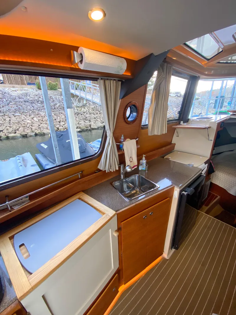 Slide: The Image of Interior of 2017 Ranger Tugs R-29 CB, featuring a compact kitchen with sink and window view. - 18